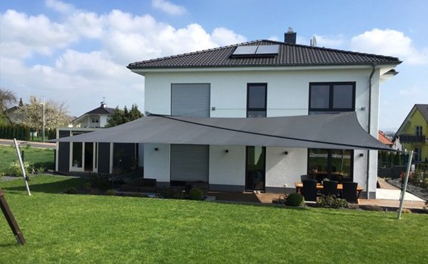 Manuell aufrollbares Sonnensegel an einem Haus mit Garten