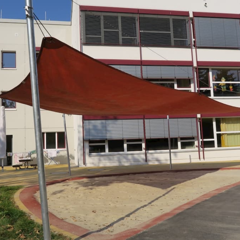 Rotes Sonnensegel über Sandkasten