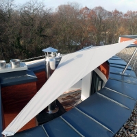 Ein dreiecksförmiges, fixes Sonnensegel über einer Terasse